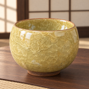 Cuenco amarillo y oliva con esmalte craquelado, ambientado en sala de té japonesa.