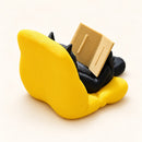 Figura decorativa de gato negro lector en sillón amarillo